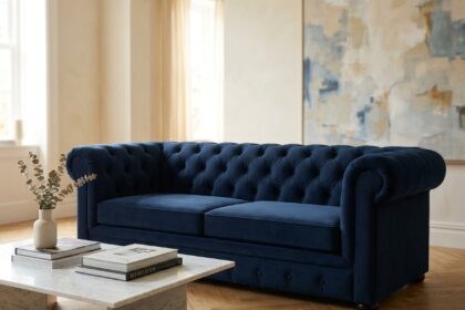 Canapé capitonné bleu marine en velours dans un salon contemporain au parquet en chêne et murs ivoire