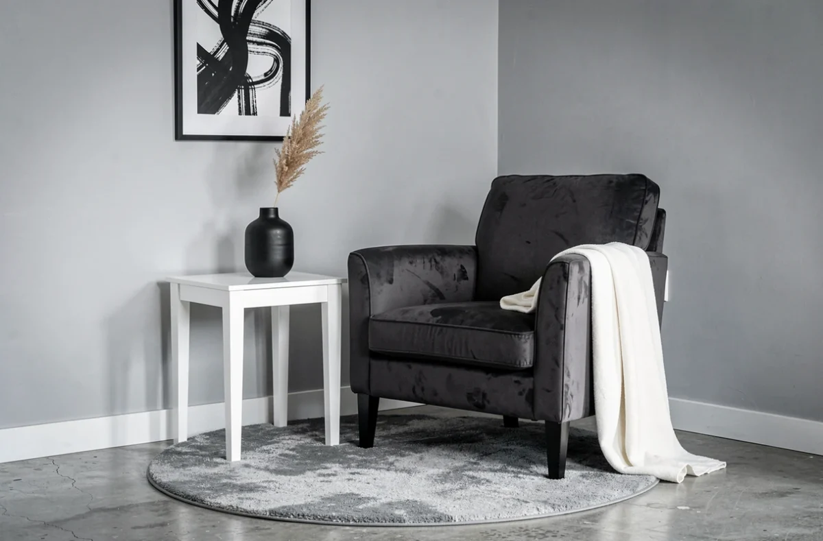 Coin salon décoré en velours gris anthracite avec vase noir et impression abstraite noir et blanc dans un petit espace