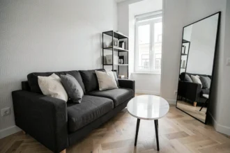 Salon noir gris blanc élégant dans un petit appartement avec canapé anthracite, table basse en marbre blanc et parquet en chêne