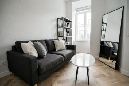 Salon noir gris blanc élégant dans un petit appartement avec canapé anthracite, table basse en marbre blanc et parquet en chêne