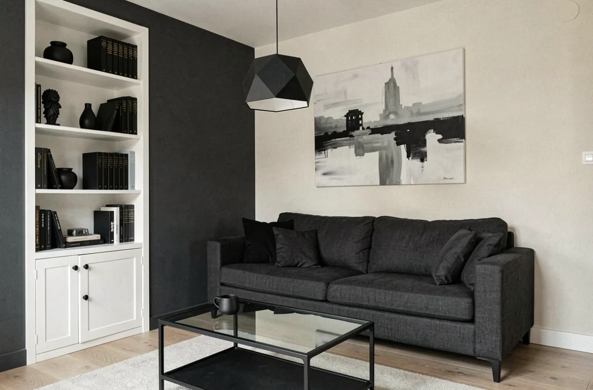 Salon parisien compact en noir blanc gris avec bibliothèque intégrée blanche, canapé anthracite et tableau abstrait en niveaux de gris
